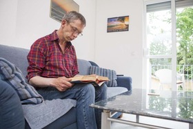 Ein Bewohner in der Danziger Straße sitzt auf dem Sofa und liest ein Buch