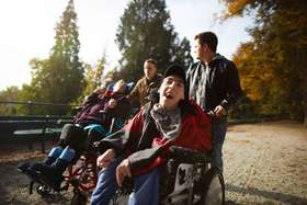 Betreuer mit Mnnern im Rollstuhl beim Spatziergang